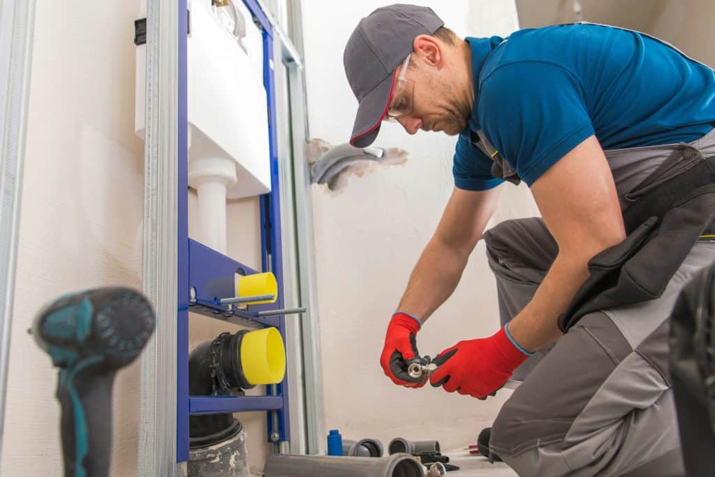 Image of plumber installing a new feature in bathroom.
