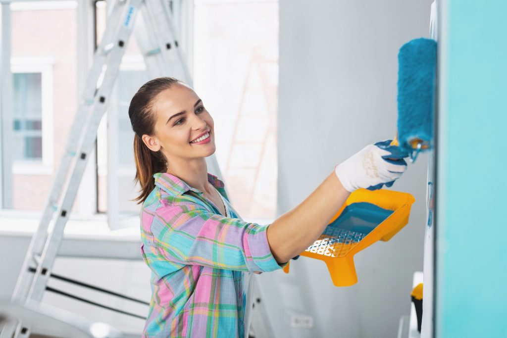 Woman painting a light blue wall representing a painting franchise